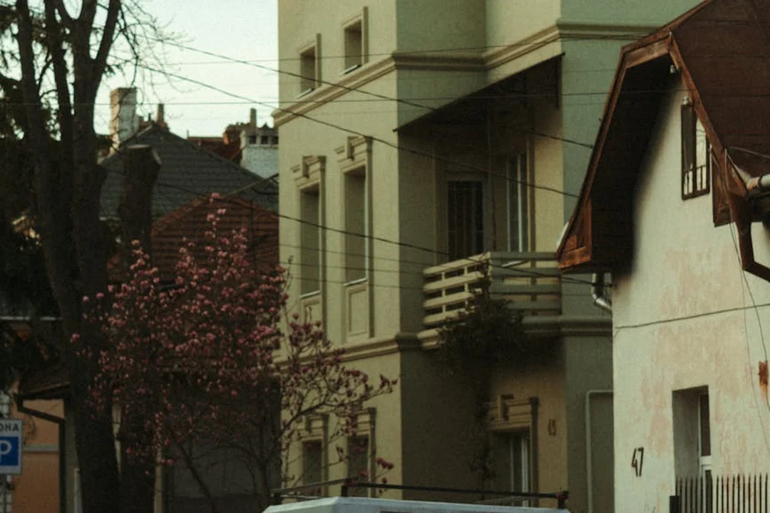 A residential street with a parked car and multi-story homes, illustrating neighborhood context when evaluating HOA options during the home purchase.