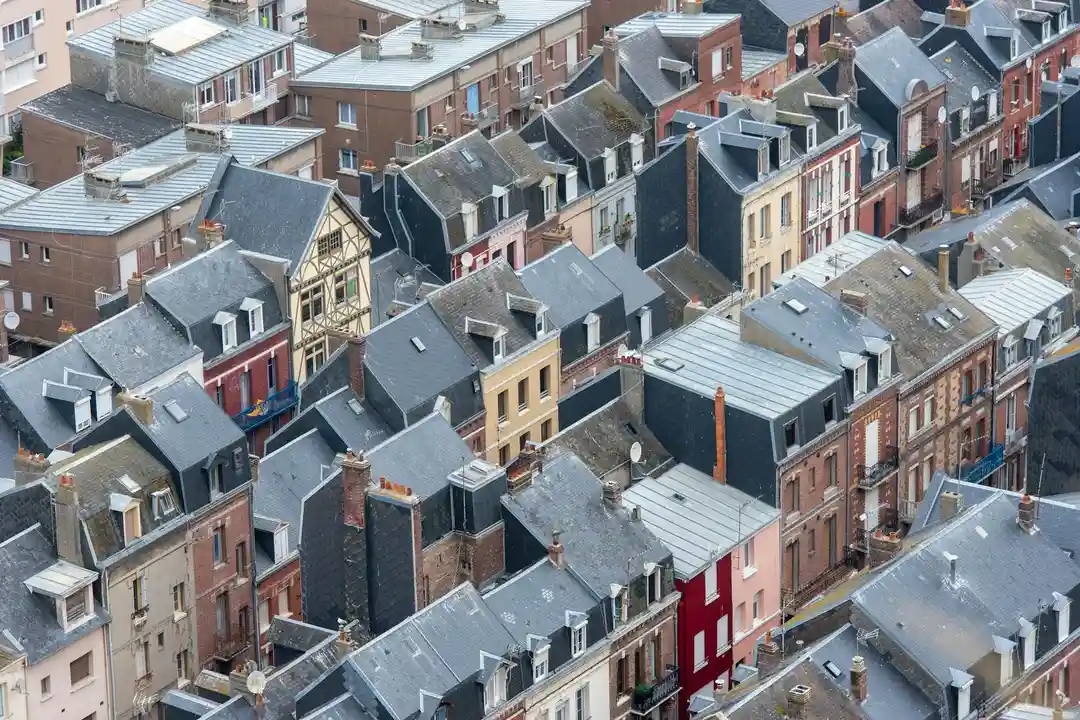 Aerial view of a dense urban neighborhood with closely packed row houses and slate-gray rooftops