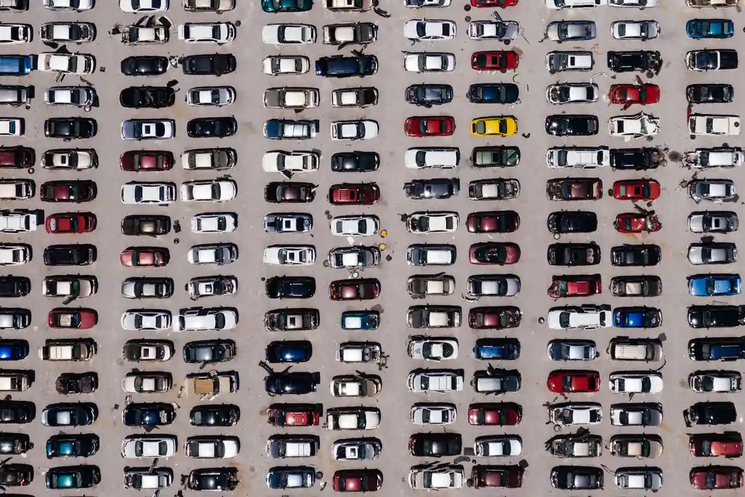 Aerial view of a large parking lot filled with rows of cars