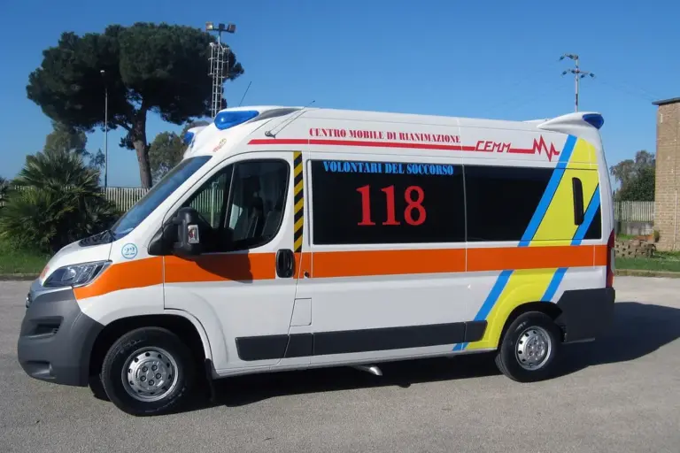 Side view of an emergency ambulance parked on a street with orange and blue markings.
