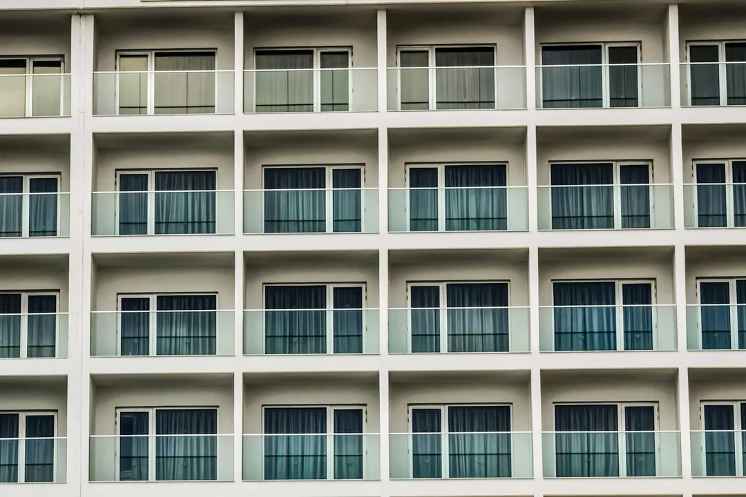 Facade of a modern multi-story apartment building with repeating balconies and windows.