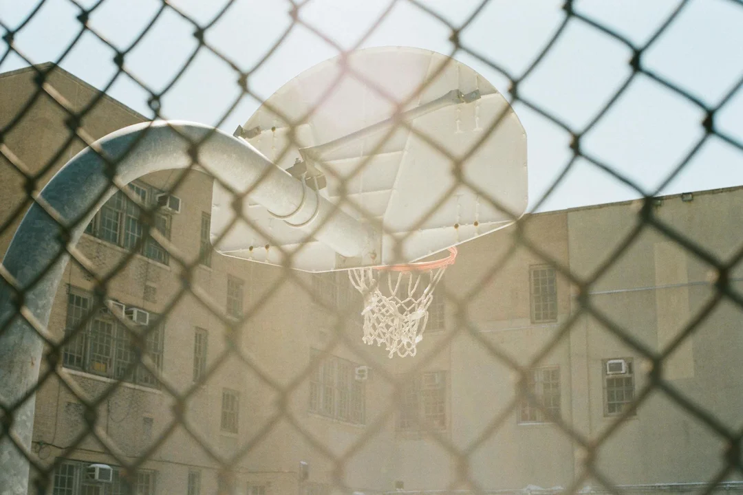 Basketball hoop visible through a chain-link fence, representing an HOA community amenity.