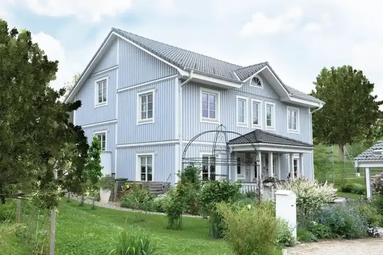 Blue two-story house with well-kept lawn and trees in a suburban HOA neighborhood.