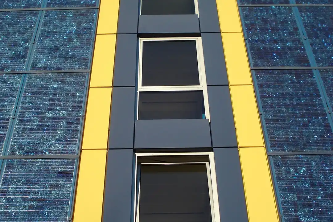 A modern building facade with blue glass panels and yellow vertical accents, featuring a narrow central column of windows.