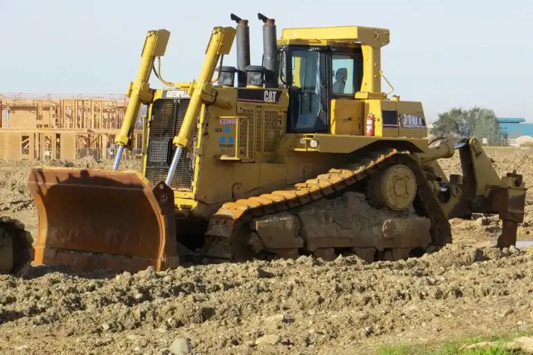 Yellow bulldozer on a dirt construction site performing earthmoving work.