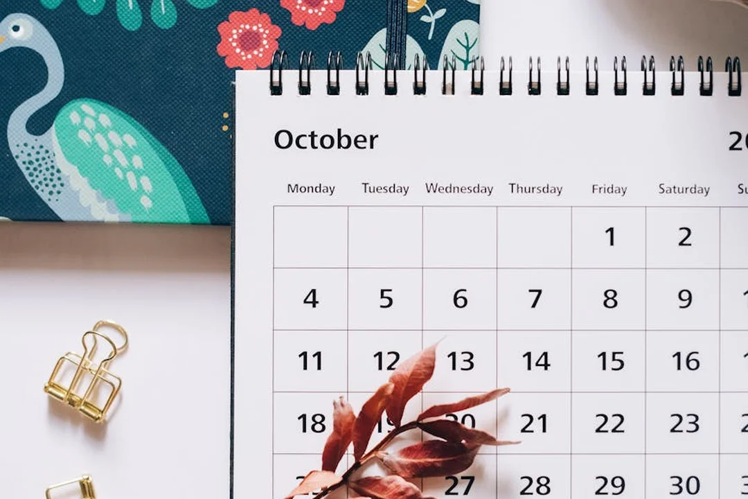 An open October calendar with decorative leaves and gold binder clips, representing deadlines for HOA approvals.
