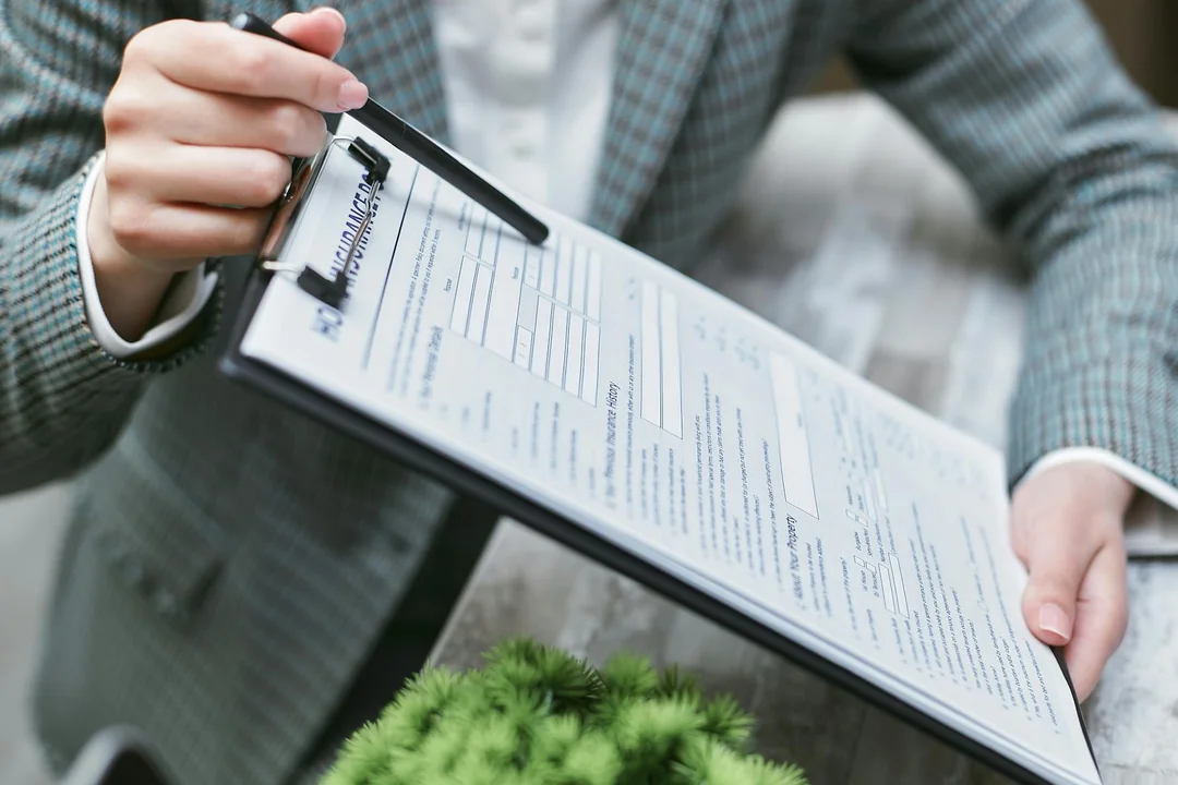 Close-up of a person in a business suit holding a clipboard and reviewing an insurance certificate form.
