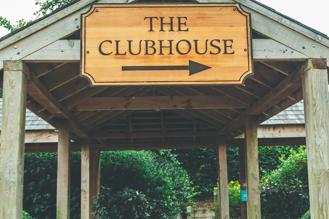 Wooden pavilion framing a sign that reads The Clubhouse with an arrow, denoting the clubhouse as a central HOA amenity.