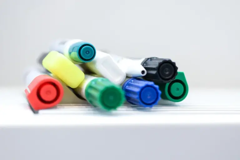 Close-up of colorful marker caps stacked on a white surface