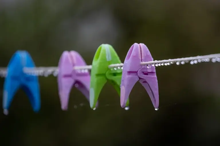 Close-up of colorful plastic clothespins on a clothesline with water droplets clinging to the line.