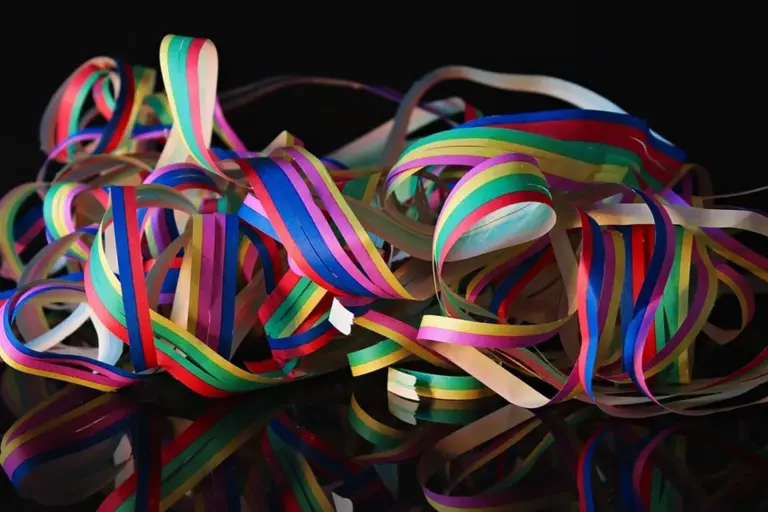 Close-up of multicolored ribbons tangled together on a dark surface.