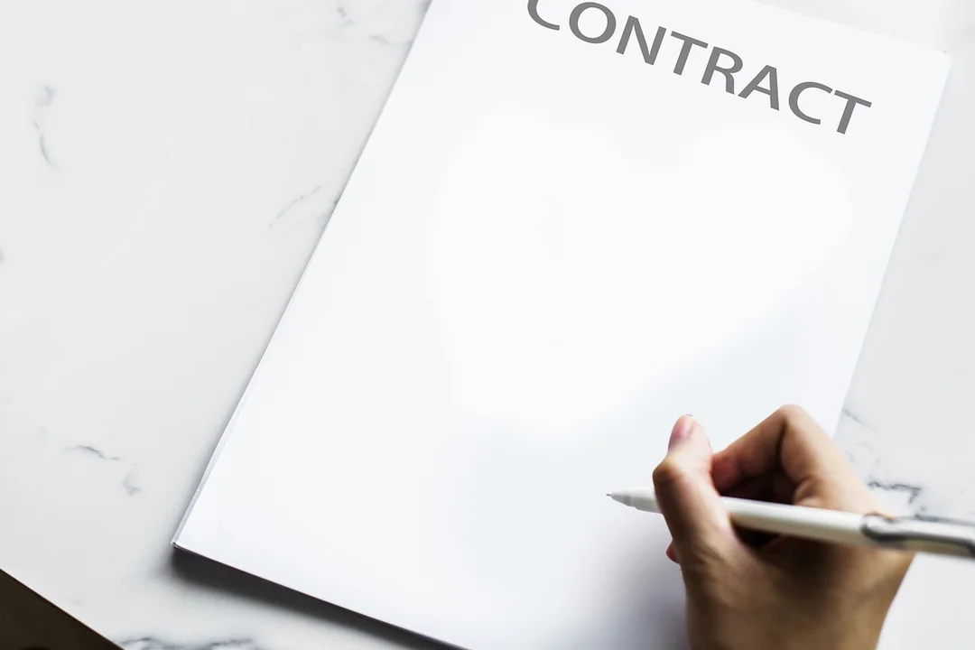 Close-up of a hand signing a contract with a white pen on a marble surface, symbolizing formal mediation agreements.