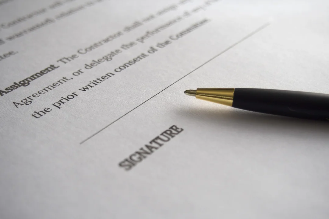 Close-up of a contract with a pen resting near the signature line, illustrating the signing step in amending HOA documents.