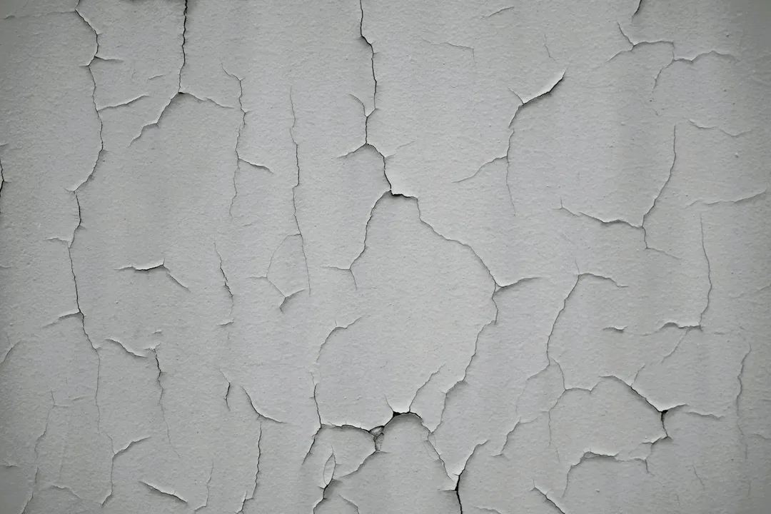 Close-up of a wall with extensive cracks and peeling paint, suggesting potential foundation-related damage.