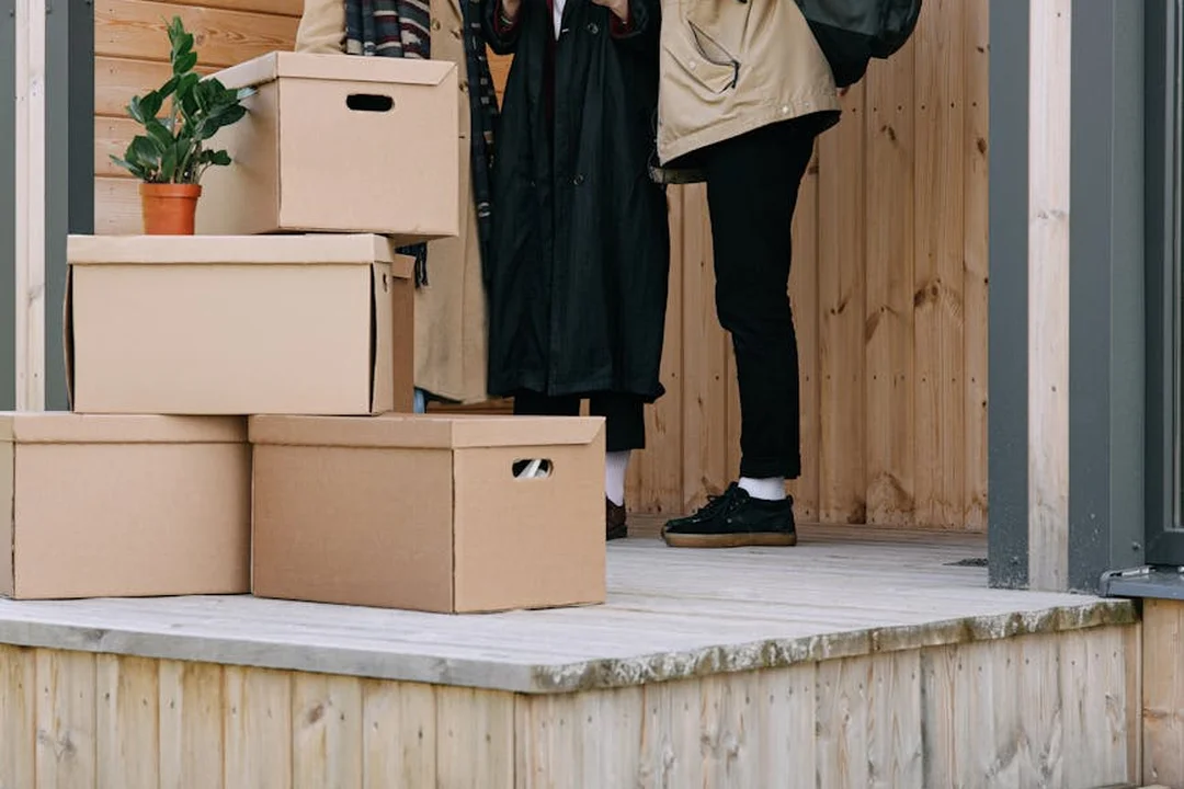 Delivery boxes on a porch with a person standing nearby