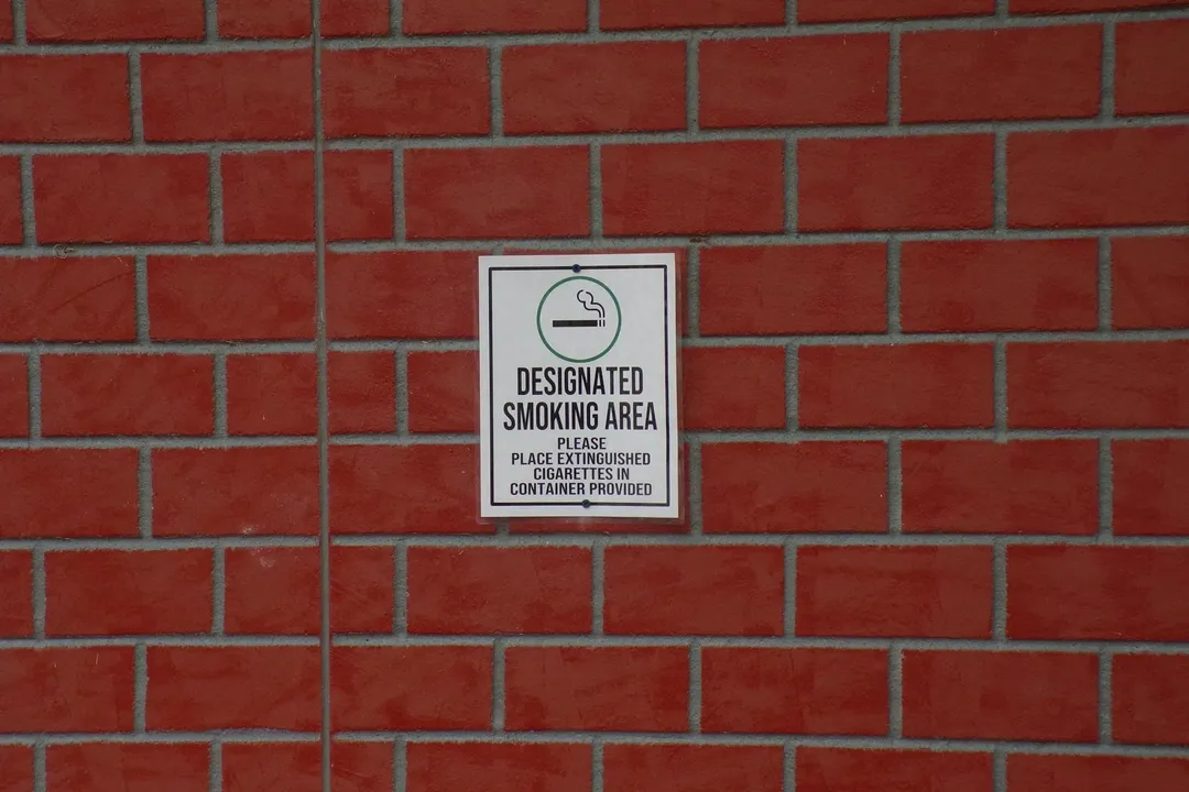 White rectangular sign with the words 'DESIGNATED SMOKING AREA' mounted on a red brick wall