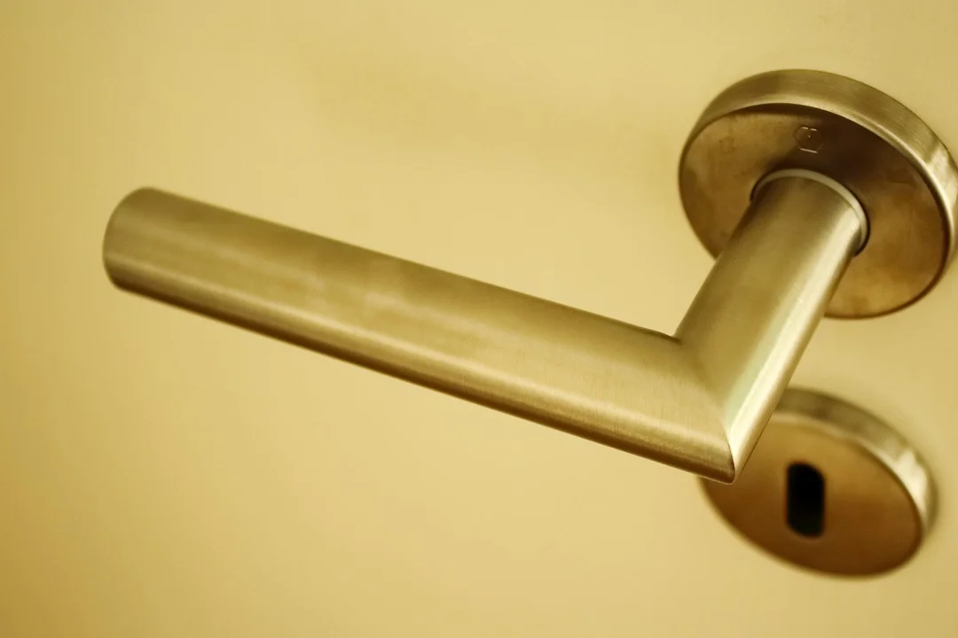 Close-up of a brass door handle on a beige door