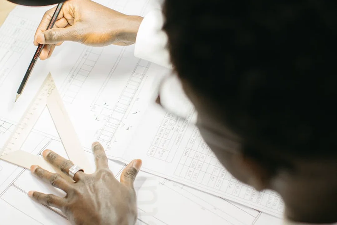 Close-up of hands drafting architectural plans with a pencil and ruler on blueprints