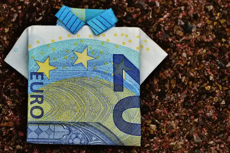 Origami-style folded euro banknote on a dark textured surface.