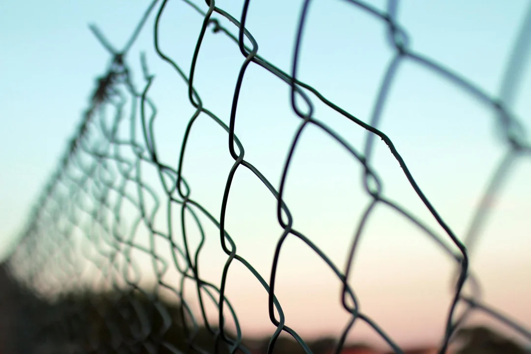 Close-up of a chain-link fence with a blurred horizon and sky in the background