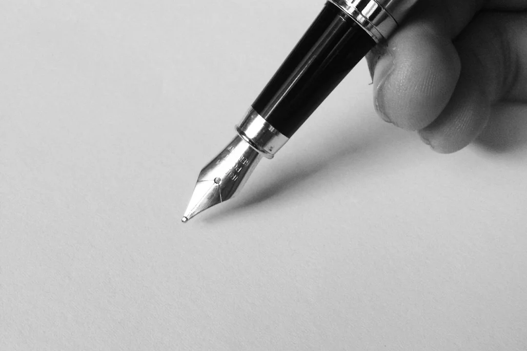 Close-up of a fountain pen poised to write on blank paper, symbolizing drafting HOA letters.