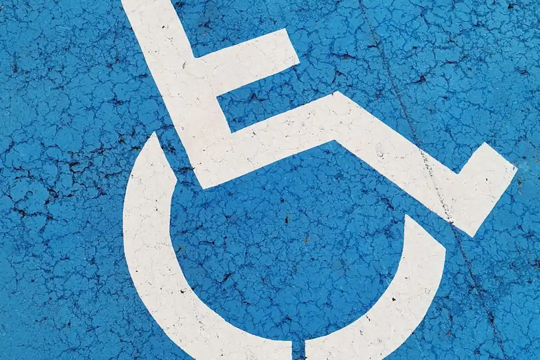 Blue wheelchair-accessible parking symbol painted on cracked pavement