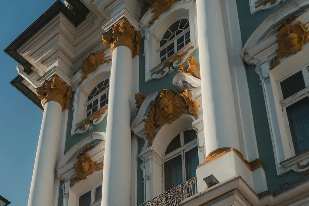 Historic building with tall white columns and gold decorative accents on a blue facade