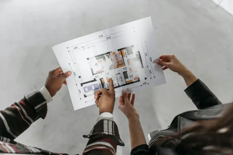 Group of hands holding and examining an architectural blueprint for appealing a denied HOA request