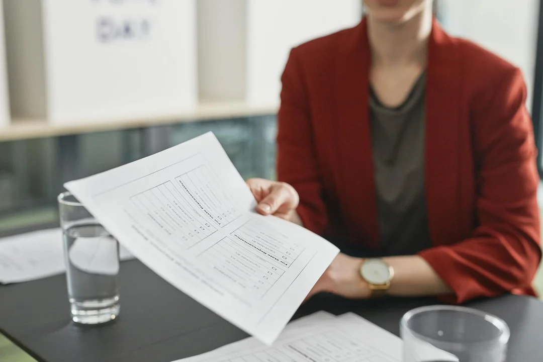 Professional in a red blazer reviews documents at a conference table, symbolizing fiduciary duties and conflict management in HOA governance.