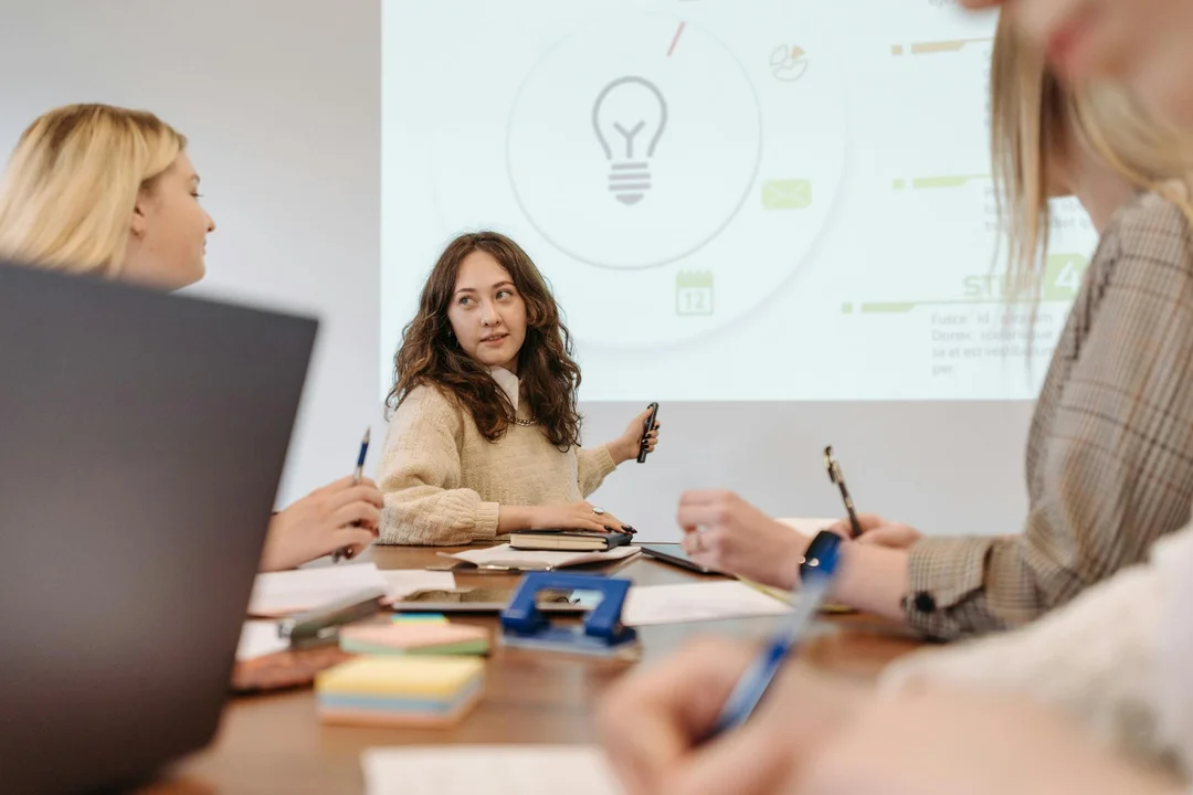 Group of HOA board members in a leadership development workshop around a table with a presenter and a projected slide showing a lightbulb icon.