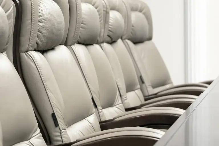 Rows of beige leather conference chairs in a boardroom.