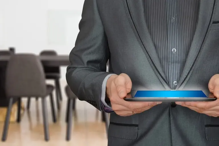 Professional in a suit holding a tablet in a conference room