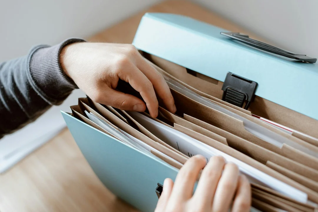 Person organizing documents in a blue binder, illustrating preparation for updating HOA bylaws