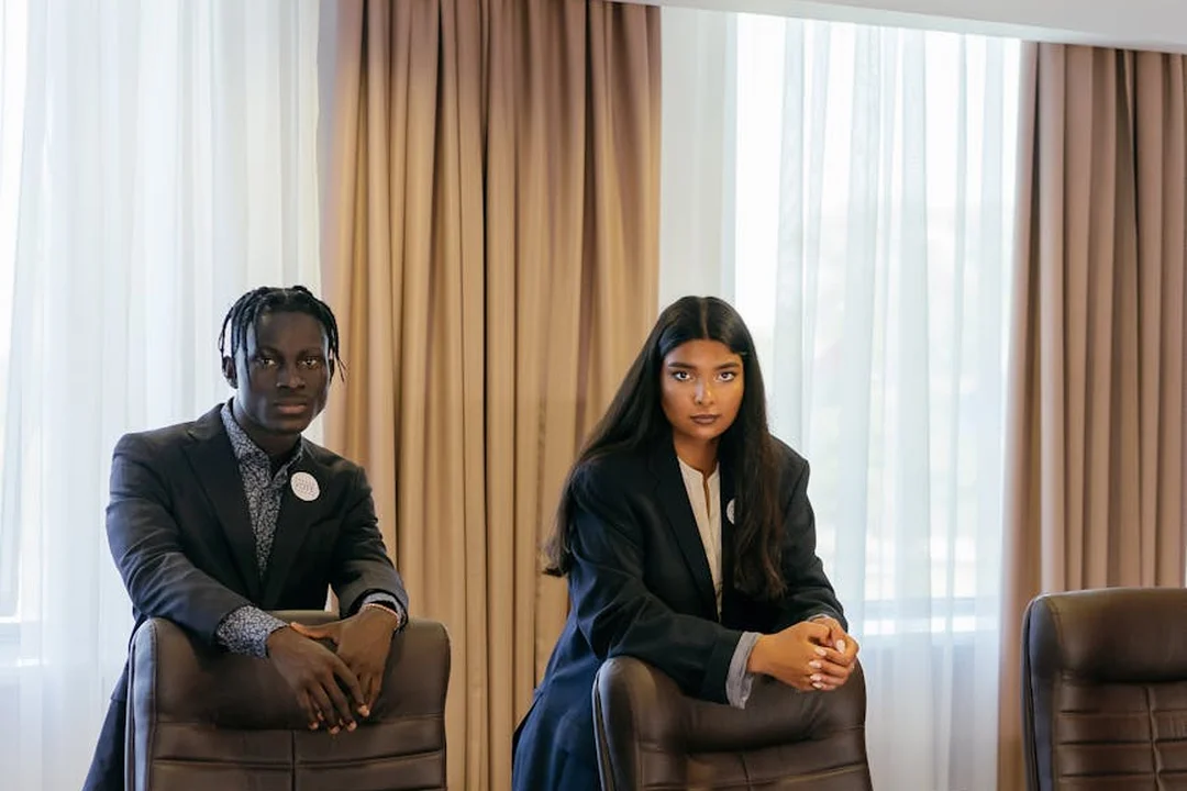 Two professionals in business attire sit in office chairs in a conference room with large windows, ready to discuss the HOA dissolution process.