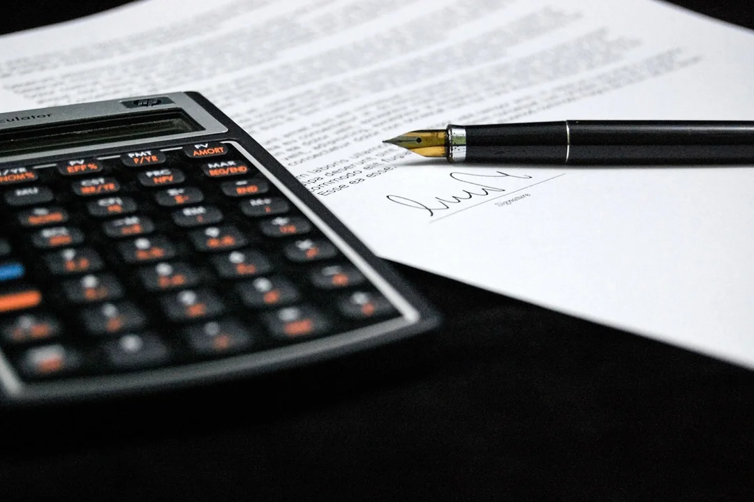 Close-up of a calculator and a pen on a signed document