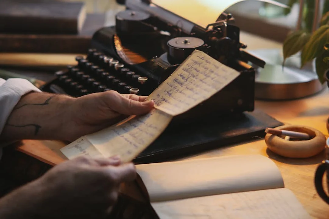 Hands typing on an old-fashioned typewriter with handwritten notes at a desk