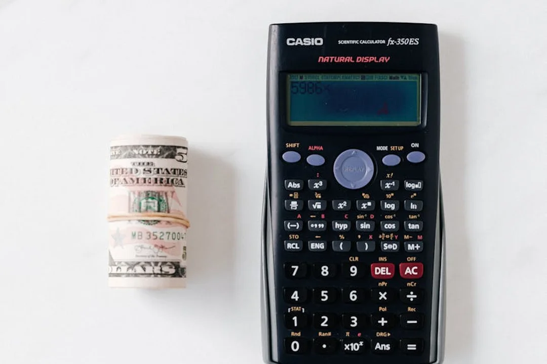 Casio calculator and a rolled stack of U.S. dollar bills on a white surface, symbolizing budgeting and fee calculation for HOA.