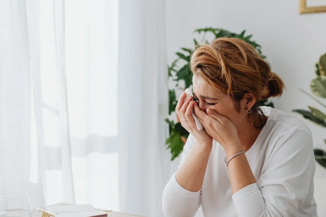 Woman sitting at a table wiping tears, reflecting stress over HOA fees and budgeting decisions.