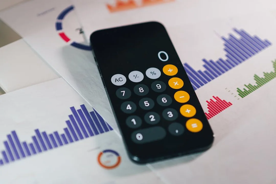 Close-up of a calculator resting on financial charts and graphs, illustrating budgeting and tax considerations.