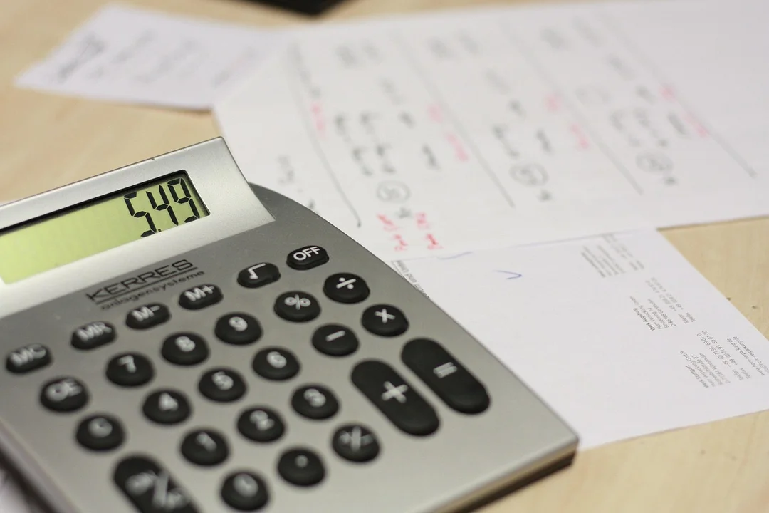 Calculator displaying a number on the screen with scattered bills and envelopes, representing HOA fees and potential special assessments.