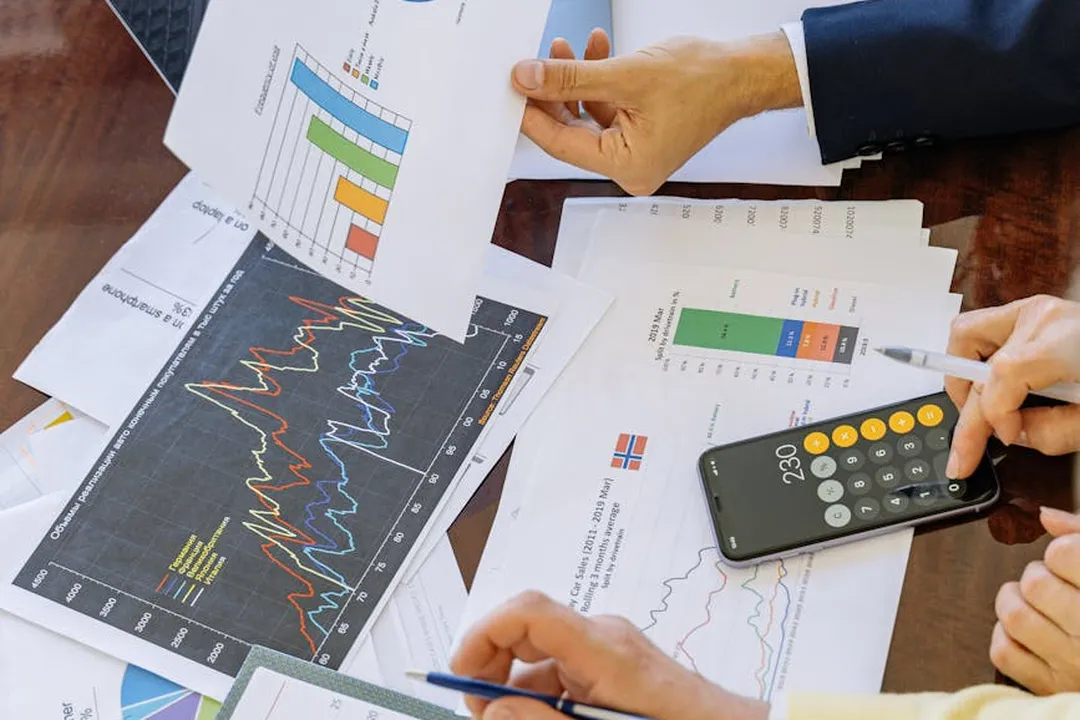 Hands reviewing charts and financial documents with a calculator on a table, illustrating analysis after a request for HOA financial records is denied.