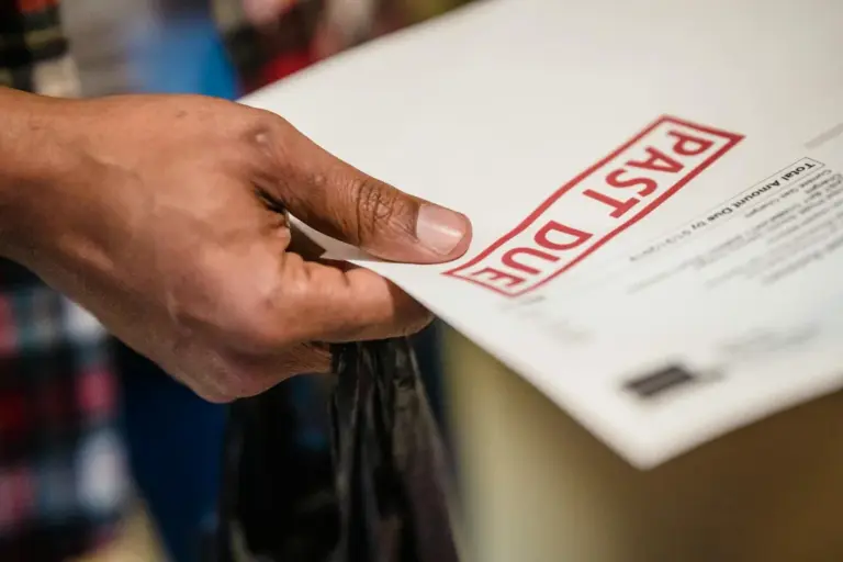 Close-up of a hand holding a document with a large red stamp reading 'PAID DUE'.