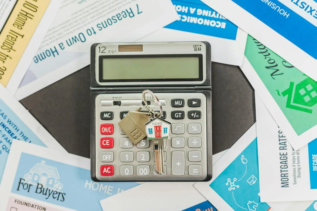 Calculator and keys resting on HOA-related documents and blueprints, symbolizing budgeting and decision-making when buying an HOA home.