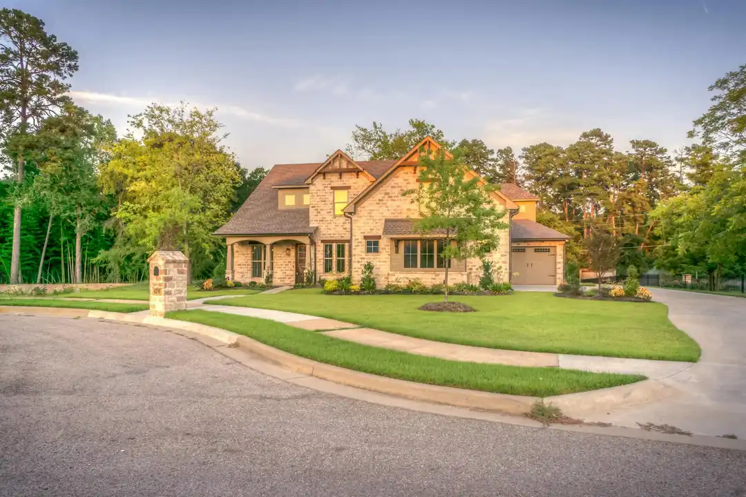 Front view of a well-kept single-family home in an HOA neighborhood with a curved driveway and lush green lawn.