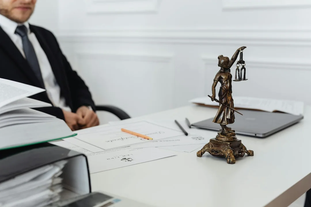 A professional seated at a desk with legal documents and a small Lady Justice statue, symbolizing HOA legal considerations.