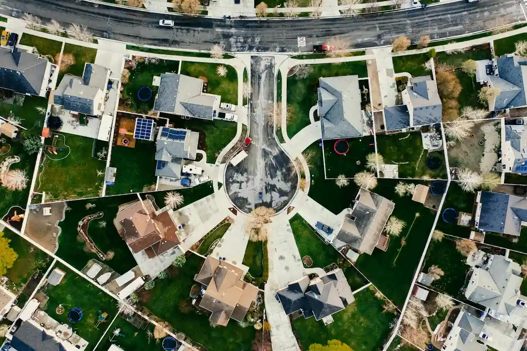 Aerial view of a suburban HOA community with cul-de-sacs, green lawns, and houses.