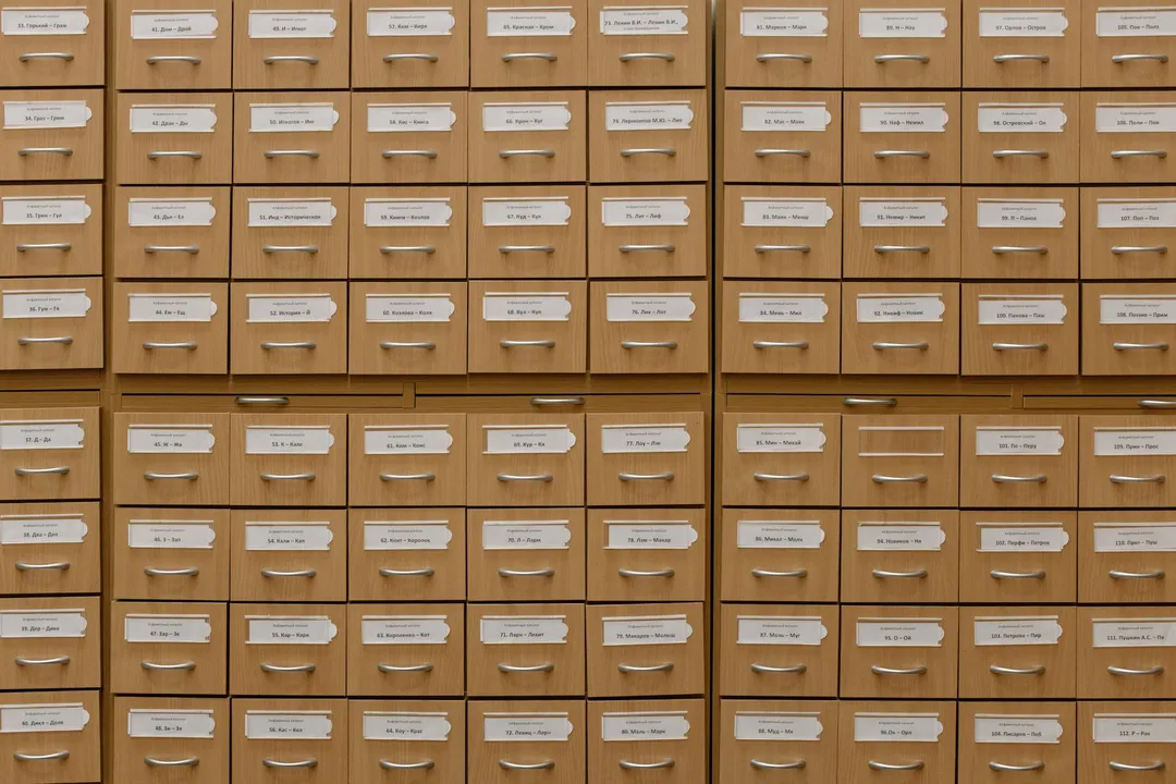 A wall of uniform wooden filing cabinets with small labeled drawers, suggesting orderly storage of HOA records.