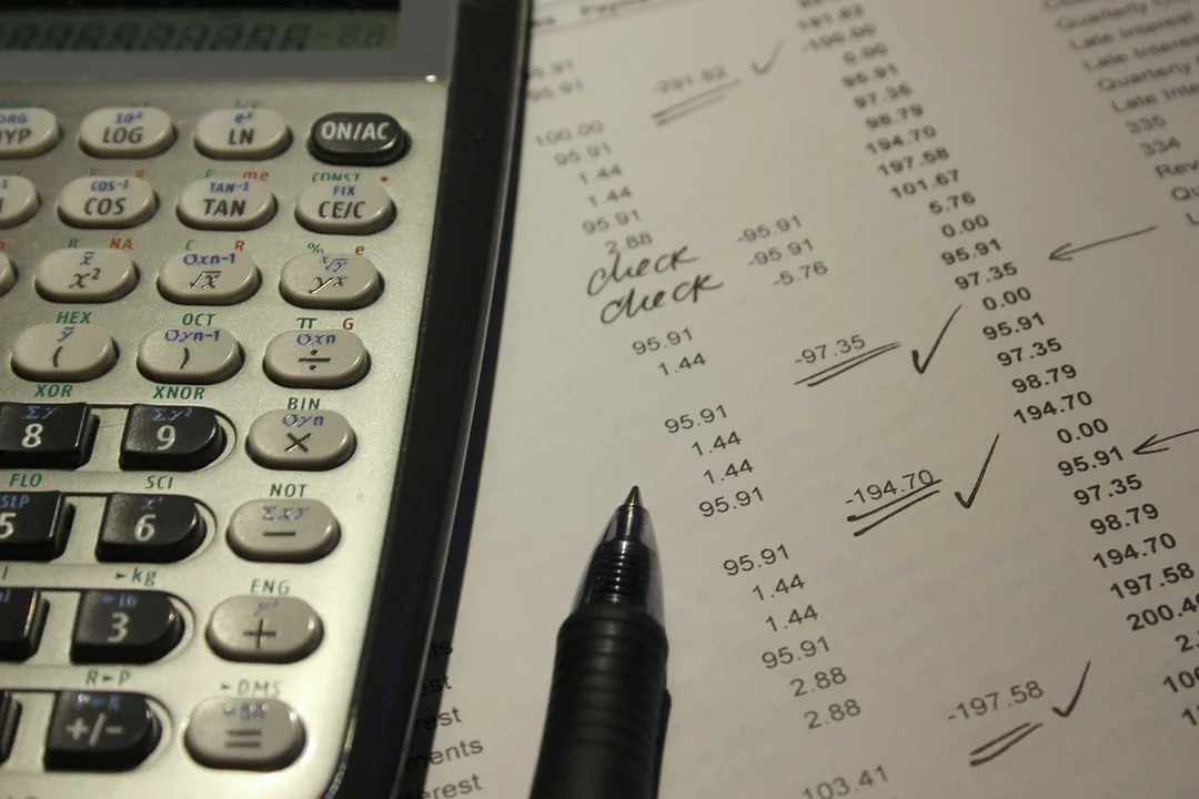 Close-up of a calculator and a financial ledger with a pen, illustrating HOA financial records and access considerations