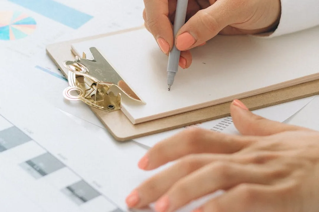 Close-up of hands signing documents on a clipboard with keys nearby, representing HOA records and privacy considerations.