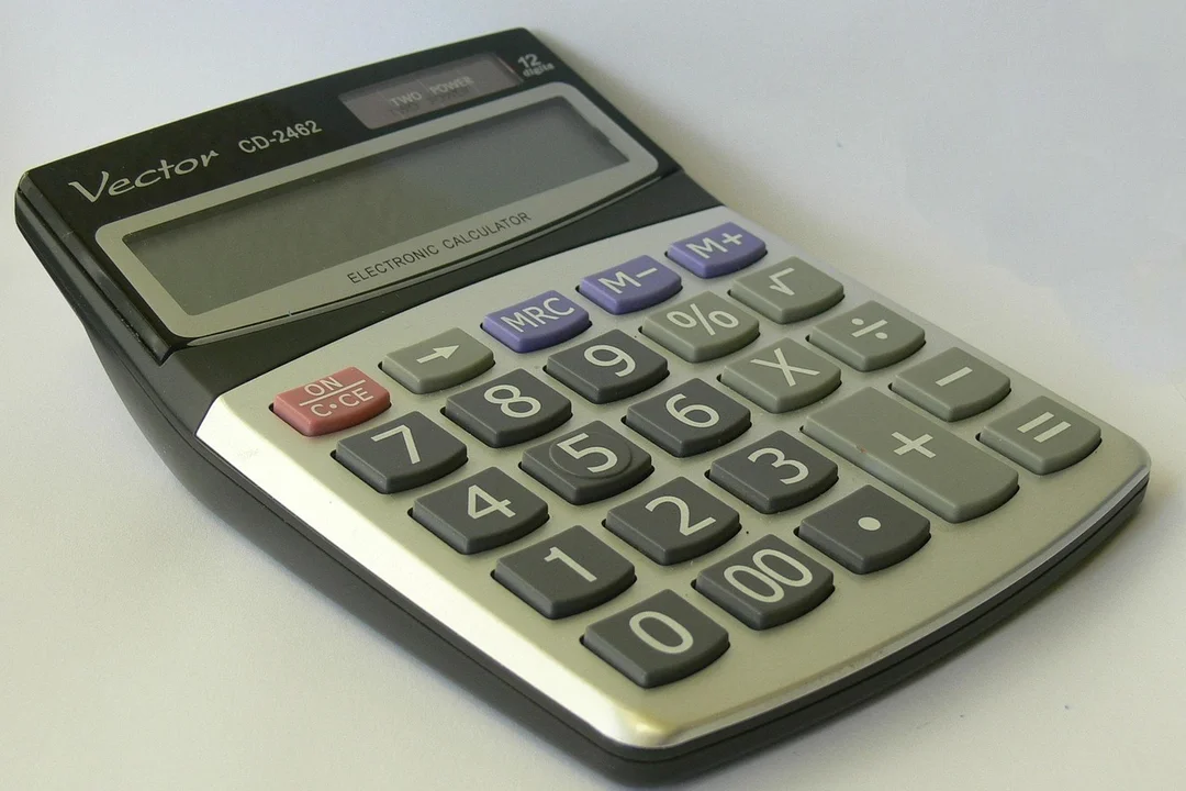 A handheld calculator with a large display and gray keys on a light surface